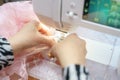 Sewing delicate pink lace fabric on a sewing machine in a well-lit workspace during daytime Royalty Free Stock Photo