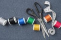 Sewing items: tailoring scissors, measuring tape, spools of multicolored threads. Sewing accessories on sewing cloth.