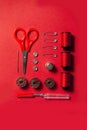 Sewing kit accessories and tools for needle work in red. Tape measure, pins, scissors, buttons, prewound bobbins, thimble, thread Royalty Free Stock Photo