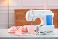 Sewing machine with fabric and other supplies on white table in workshop Royalty Free Stock Photo