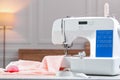 Sewing machine with fabric and other supplies on white table in workshop, space for text Royalty Free Stock Photo