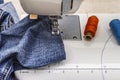Sewing machine foot on denim. Scissors, spools of thread. Stands on a table Royalty Free Stock Photo