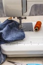 Sewing machine foot on denim. Scissors, spools of thread. Stands on a table Royalty Free Stock Photo