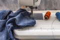 Sewing machine foot on denim. Scissors, spools of thread. Stands on a table Royalty Free Stock Photo