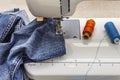 Sewing machine foot on denim. Scissors, spools of thread. Stands on a table Royalty Free Stock Photo