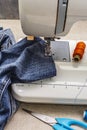 Sewing machine foot on denim. Scissors, spools of thread. Stands on a table Royalty Free Stock Photo