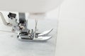 Sewing machine foot working on white fabric during crafting session Royalty Free Stock Photo