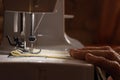 Sewing machine and old grandmother`s hand in a dark room sew