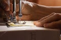 Sewing machine and old grandmother`s hand in a dark room sew