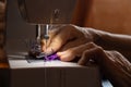 Sewing machine and old grandmother`s hand in a dark room sew