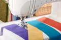 Sewing machine with a strips of fabrics on the background of stack of colorful quilting fabrics