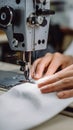 Sewing machine works on white fabric, set in a blurred workshop setting Royalty Free Stock Photo