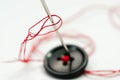 Sewing needle with red thread, black button close up macro shot Royalty Free Stock Photo