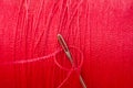 Sewing needle on red thread spool background Royalty Free Stock Photo