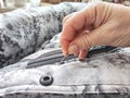 Sewing with a needle and thread on a mottled spotted fabric by hand. A middle-aged or mature hand with a sewing needle Royalty Free Stock Photo