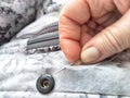 Sewing with a needle and thread on a mottled spotted fabric by hand. A middle-aged or mature hand with a sewing needle Royalty Free Stock Photo