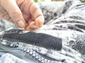 Sewing with a needle and thread on a mottled spotted fabric by hand. A middle-aged or mature hand with a sewing needle Royalty Free Stock Photo