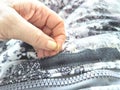 Sewing with a needle and thread on a mottled spotted fabric by hand. A middle-aged or mature hand with a sewing needle Royalty Free Stock Photo