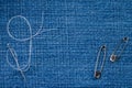 Sewing needle with a white thread and two pins on a denim fabric Royalty Free Stock Photo