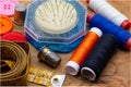 Sewing objects. Thimbles, colored threads, meter tape, colored buttons and pins on wooden background.