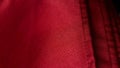 Sewing stitch on maroon textiles. Burgundy fabric stitched thread, textile background. Close-up