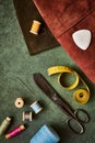 Sewing supplies, antique scissors, spools of thread, and tailors meter on green textured background, flat lay