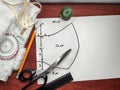 Sewing supplies on background of a drawn pattern of a medical face mask. Scissors, ruler, pencil, thread, fabric and white sheet