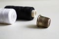 Sewing supplies. Two reels with black and white threads, thimble on a gray background Royalty Free Stock Photo