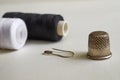 Sewing supplies. Two reels with black and white threads, thimble and pin on a gray background Royalty Free Stock Photo