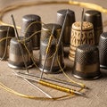 Sewing thimbles and needles on fabric Royalty Free Stock Photo