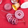 Sewing thread, buttons, thimble on red fabric Royalty Free Stock Photo