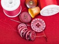 Sewing thread, buttons, thimble on red textile Royalty Free Stock Photo