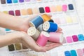 Sewing thread in hands of colorful fabric samples background Royalty Free Stock Photo