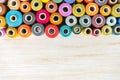 Multicolor sewing threads on white wooden background with copy space