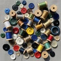 Sewing threads on wooden spools and assorted buttons are scattered on a texture Royalty Free Stock Photo
