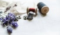 Sewing tools with fresh lavander flowers on linen background. Vintage wooden spool, braid, thimble, buttons. Royalty Free Stock Photo