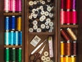 Sewing tools and multi colorful threads in wooden box, flat lay picture