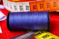 Sewing work concept: Macro close up of isolated blue thread spool, scissors and measuring tape Royalty Free Stock Photo