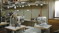Sewing workshop interior in soft defocused bokeh showing industrial machines, thread spools, shelving, lamps and a window for Royalty Free Stock Photo