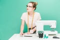 Sewing workshop. Seamstress at work. Portrait of a young dressmaker with notebook on a colored background.