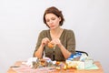 She sews toy cockerel at the table with needlework Royalty Free Stock Photo