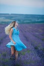 Sex appeal blond woman in airy blue dress enjoy life time vacation on fresh lavender field by walking or spinning around. Sylph