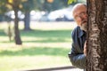 Sex stalker maniac. Voyeur and spy. Man peeking hiding behind tree. Royalty Free Stock Photo