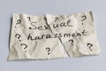 Sexual harassment concept. A torn piece of crumpled paper with many question mark signs and the words sexual harassment Royalty Free Stock Photo