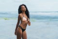 Sexy african american girl in swimwear resting on ocean beach. Young black skinned woman with curly hair stands on Royalty Free Stock Photo
