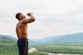 african american muscular man drinking water after sports training. Breathtaking green mountain landscape on Royalty Free Stock Photo