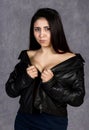 asian woman with bare shoulders wearing leather jacket and black skirt posing on a gray background Royalty Free Stock Photo