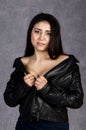 asian woman with bare shoulders wearing leather jacket and black skirt posing on a gray background Royalty Free Stock Photo