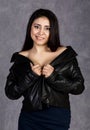 asian woman with bare shoulders wearing leather jacket and black skirt posing on a gray background Royalty Free Stock Photo