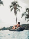 Sexy asian woman in bikini sitting on floating bean bag in luxury resort swimming pool. female looking away to the ocean in sunset Royalty Free Stock Photo